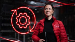 Una collaboratrice di Linde Material Handling in un capannone, con il simbolo LED rosso di un ingranaggio sullo sfondo.