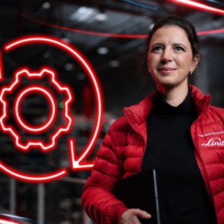 Una collaboratrice di Linde Material Handling in un capannone, con il simbolo illuminato rosso di un ingranaggio sullo sfondo.