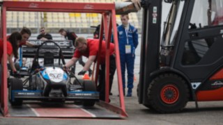 Un carrello elevatore a noleggio di Linde solleva una macchina da corsa con un dispositivo speciale durante la Formula Student sul circuito dell’Hockenheimring Un carrello elevatore a noleggio di Linde solleva una macchina da corsa con un dispositivo speciale