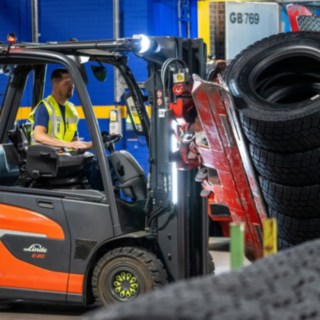 Un dipendente della Michelin Tyre PLC afferra una pila di pneumatici con una pinza montata sul carrello elevatore.