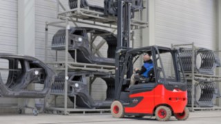 Un carrello elevatore Linde si avvicina a una scaffalatura con parti di carrozzeria