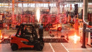 Il carrello elevatore elettrico Linde esce dalla catena di montaggio, circondato da un coloratissimo e luminoso spettacolo pirotecnico al coperto.