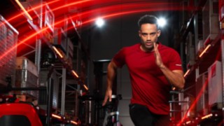 Un atleta corre in un magazzino, sullo sfondo si vede il carrello retrattile Linde Material Handling Ri16.