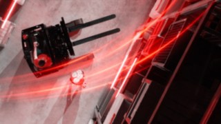 Una prospettiva aerea del carrello retrattile Linde Material Handling Ri16 con scie luminose rosse, con una persona che fa la verticale accanto al carrello.