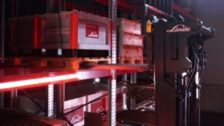 Un carrello retrattile Linde di tipo Ri16 trasporta i pallet nei pressi di una scaffalatura.