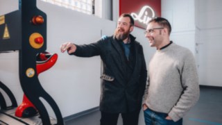 Gli esperti di automazione si scambiano opinioni davanti a un veicolo Linde, simbolo del lavoro di squadra collaborativo, dello scambio globale di conoscenze e delle soluzioni di automazione incentrate sul cliente.