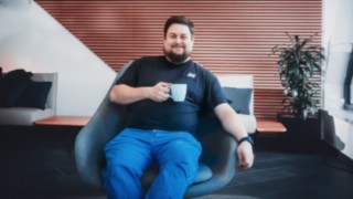 Un dipendente si rilassa su una poltrona con una tazza di caffè in mano, simbolo dell'equilibrio tra vita professionale e vita privata e dell'ambiente di lavoro positivo presso KION Automation.