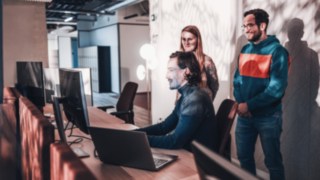 Un team dinamico lavora insieme sul posto di lavoro, dimostrando la cooperazione e lo spirito di squadra che caratterizzano KION Automation.