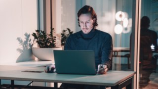 Un project manager lavora concentrato al computer portatile in un moderno ambiente d'ufficio, simbolo di lavoro autonomo, coordinamento globale del team e reti affidabili nella gestione di progetti internazionali. 