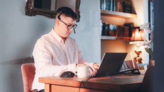 Un dipendente lavora concentrato nel proprio ufficio domestico su un laptop; la tecnologia moderna, un ambiente confortevole e condizioni di lavoro flessibili consentono un equilibrio tra vita professionale e vita privata presso KION.