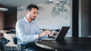 Un project manager lavora concentrato sul suo laptop e simboleggia il coordinamento di progetti complessi, dall'idea alla realizzazione presso il cliente. 