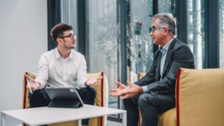 Due uomini d'affari discutono di soluzioni intralogistiche innovative, che simboleggiano il futuro dell'intralogistica e l'attenzione al cliente nella distribuzione.