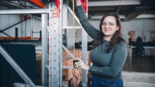Una dipendente cerca un sistema di scaffalature in un magazzino Linde per progettare soluzioni di automazione su misura nel reparto Solution Design.