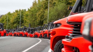Molti carrelli elevatori Linde Material Handling allineati in un parcheggio.